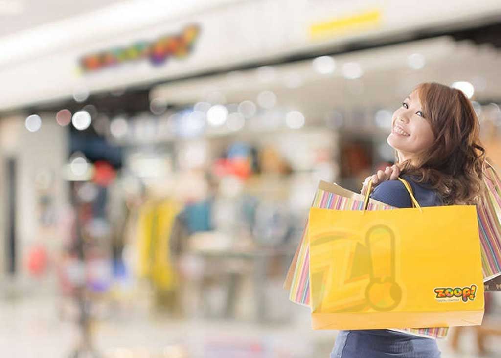 Como fazer publicidade na minha empresa para atrair mais clientes como essa moça que está com sacolas de compras num Shopping.