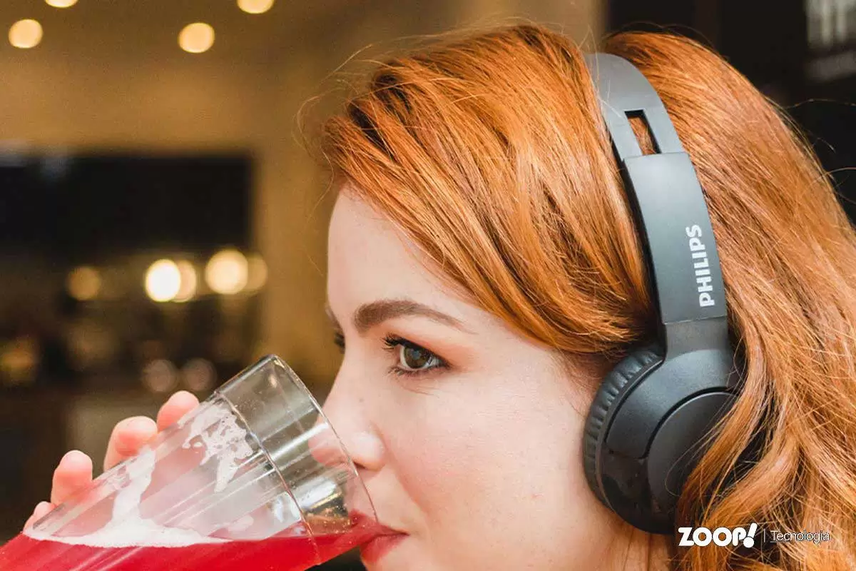 Mulher ruiva usando fone de ouvido com fio profissional marca Philips. Mulher ruiva usando fone de ouvido com fio profissional marca Philips.