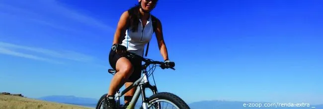 Mulher morena e jovem andando de bicicleta.