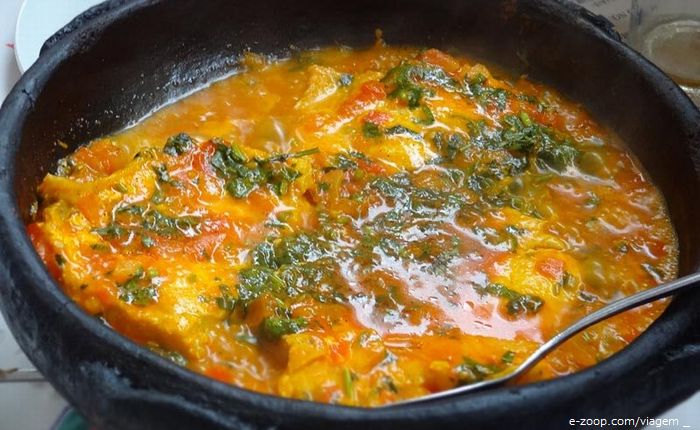 Uma panela de ferro grande cozinhando sururu ao coco.