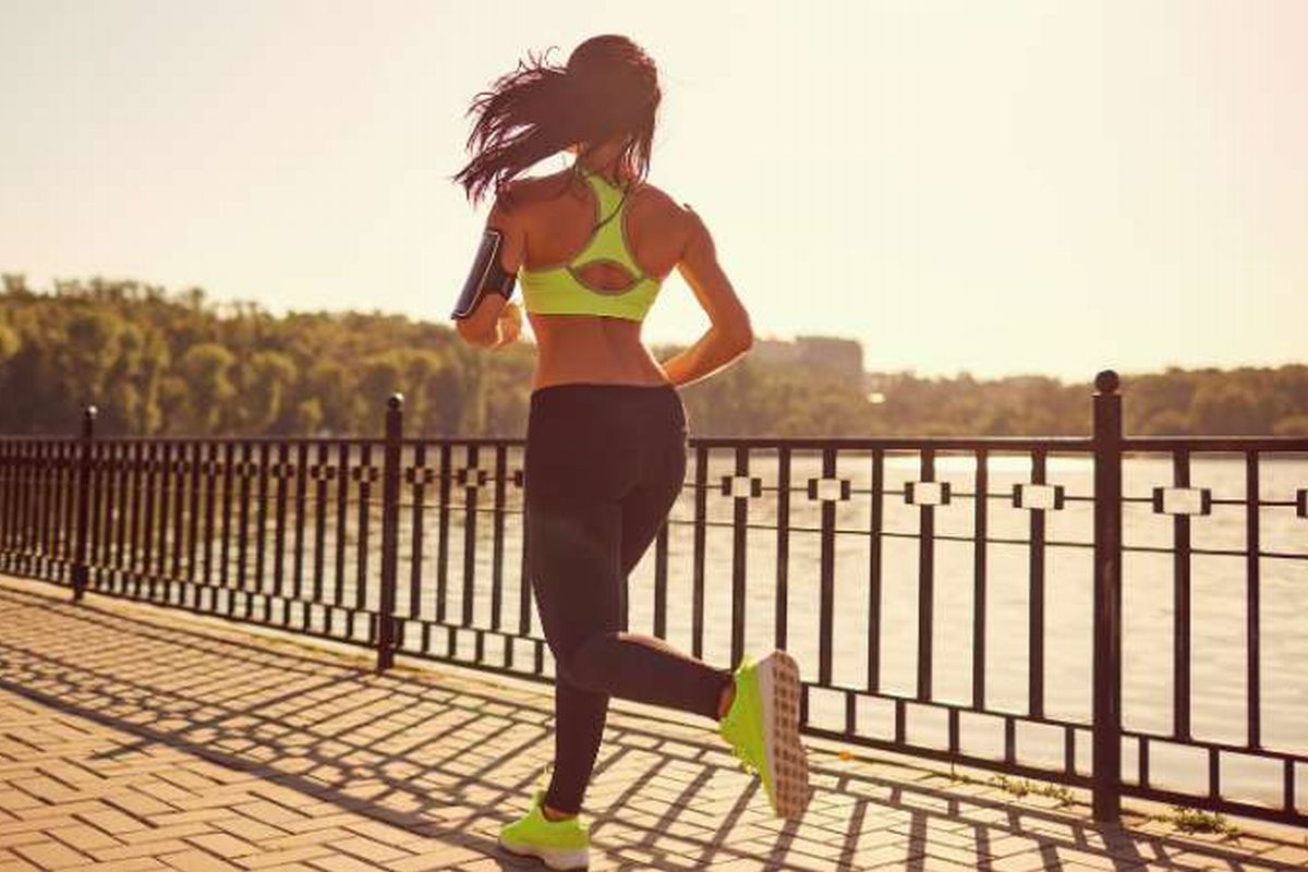 Benefícios da corrida, uma mulher praticando corrida num parque da cidade.