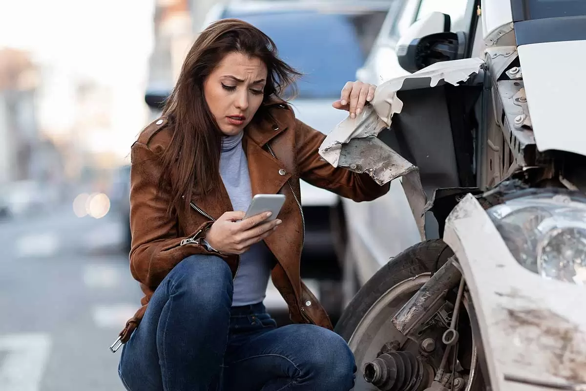 Uma mulher usando celular após um acidente de carro ilustra nosso artigo sobre sonhar com acidente de carro. Créditos da imagem: freepik.com