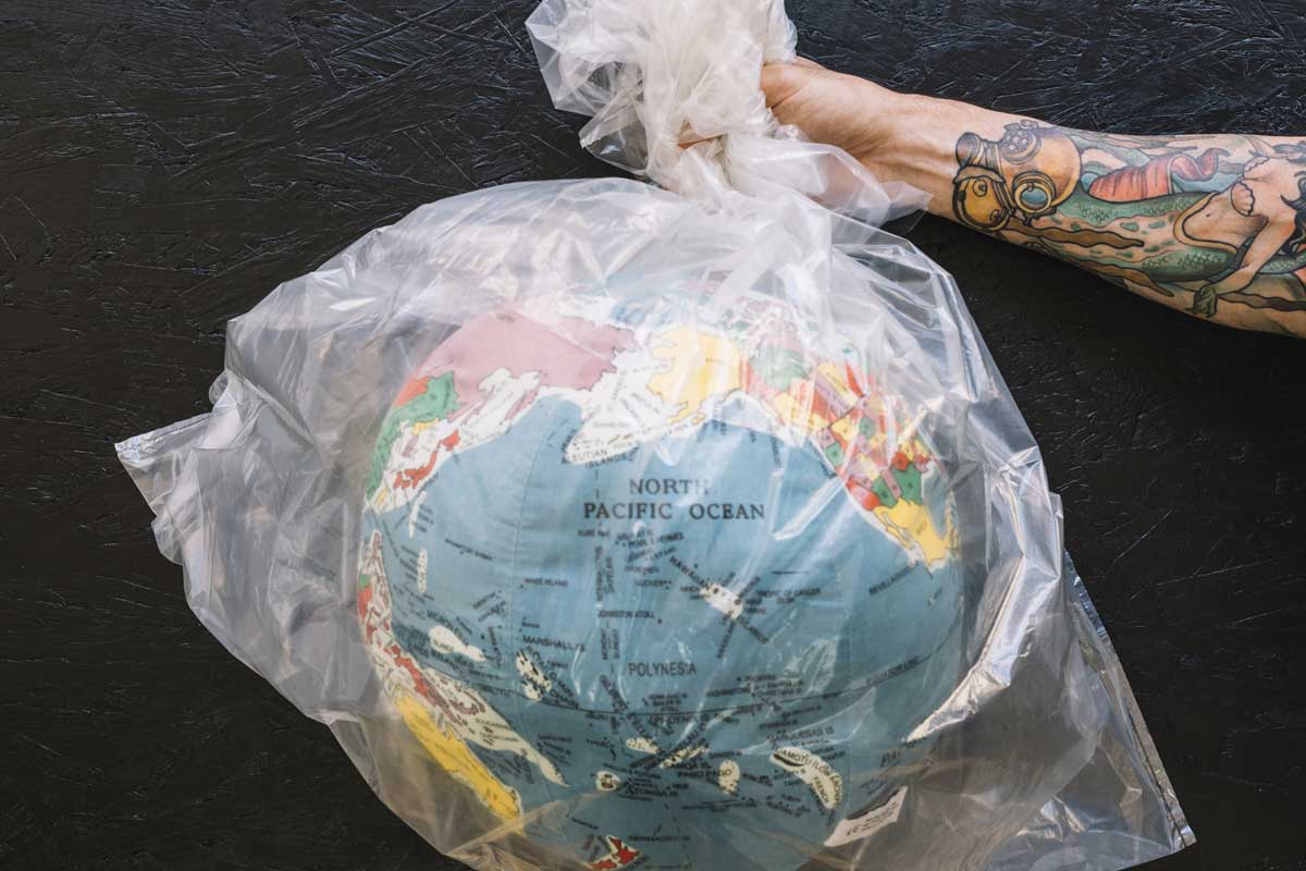 Uma pessoa segurando um saco de plástico com o globo terrestre dentro ilustra nosso artigo sobre microplásticos. Créditos da imagem: Freepik.com
