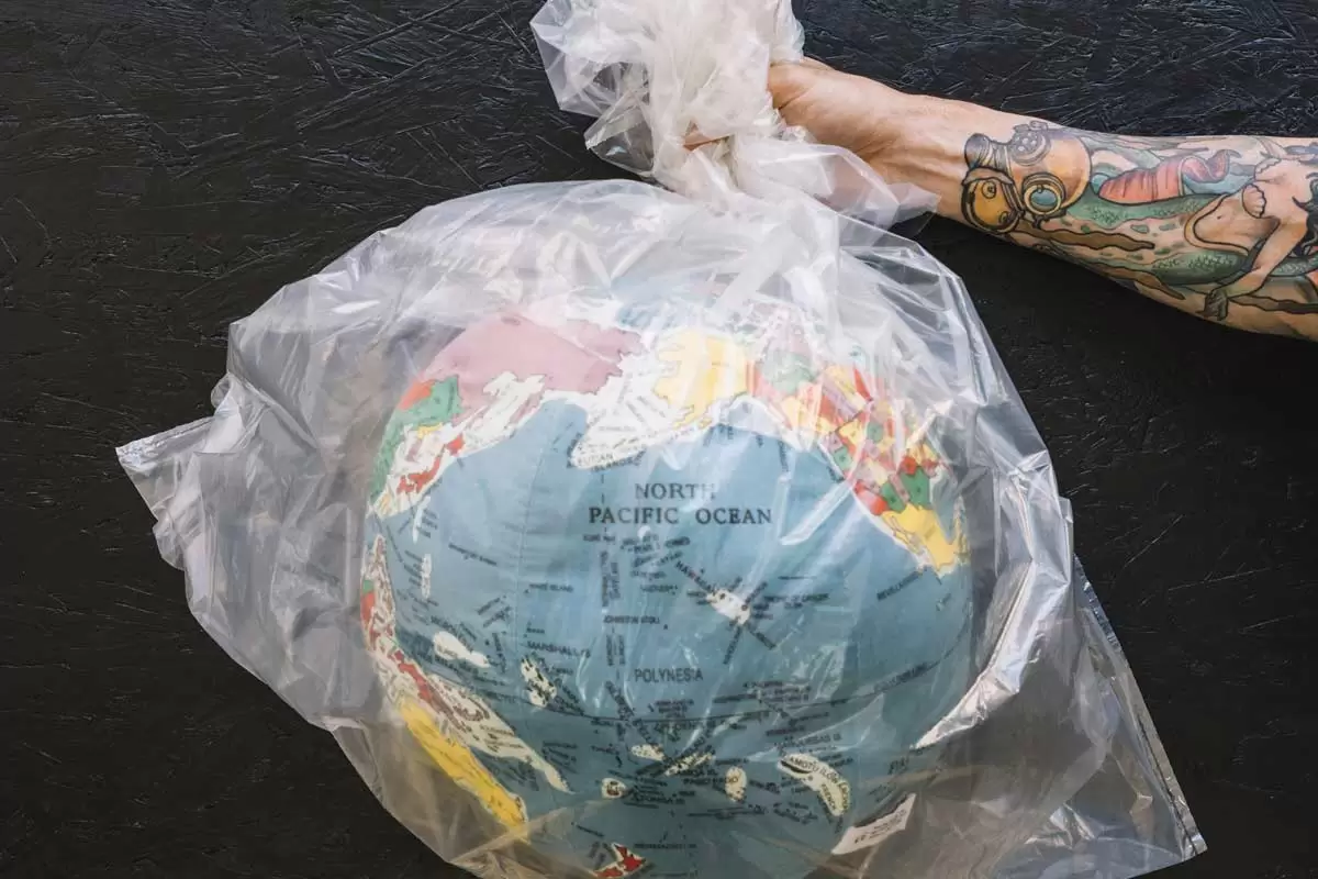 Uma pessoa segurando um saco de plástico com o globo terrestre dentro ilustra nosso artigo sobre microplásticos. Créditos da imagem: Freepik.com