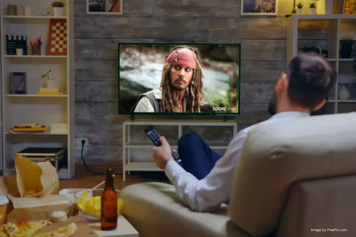 Um homem assistindo TV box pirata ilustra nosso artigo sobre: Como saber se minha TV Box é legal? Identifique aparelhos piratas.