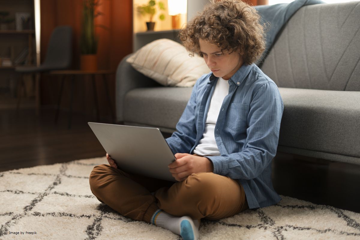 Um menino usando um notebook ilustra nosso artigo sobre: Quais os benefícios da tecnologia na educação?