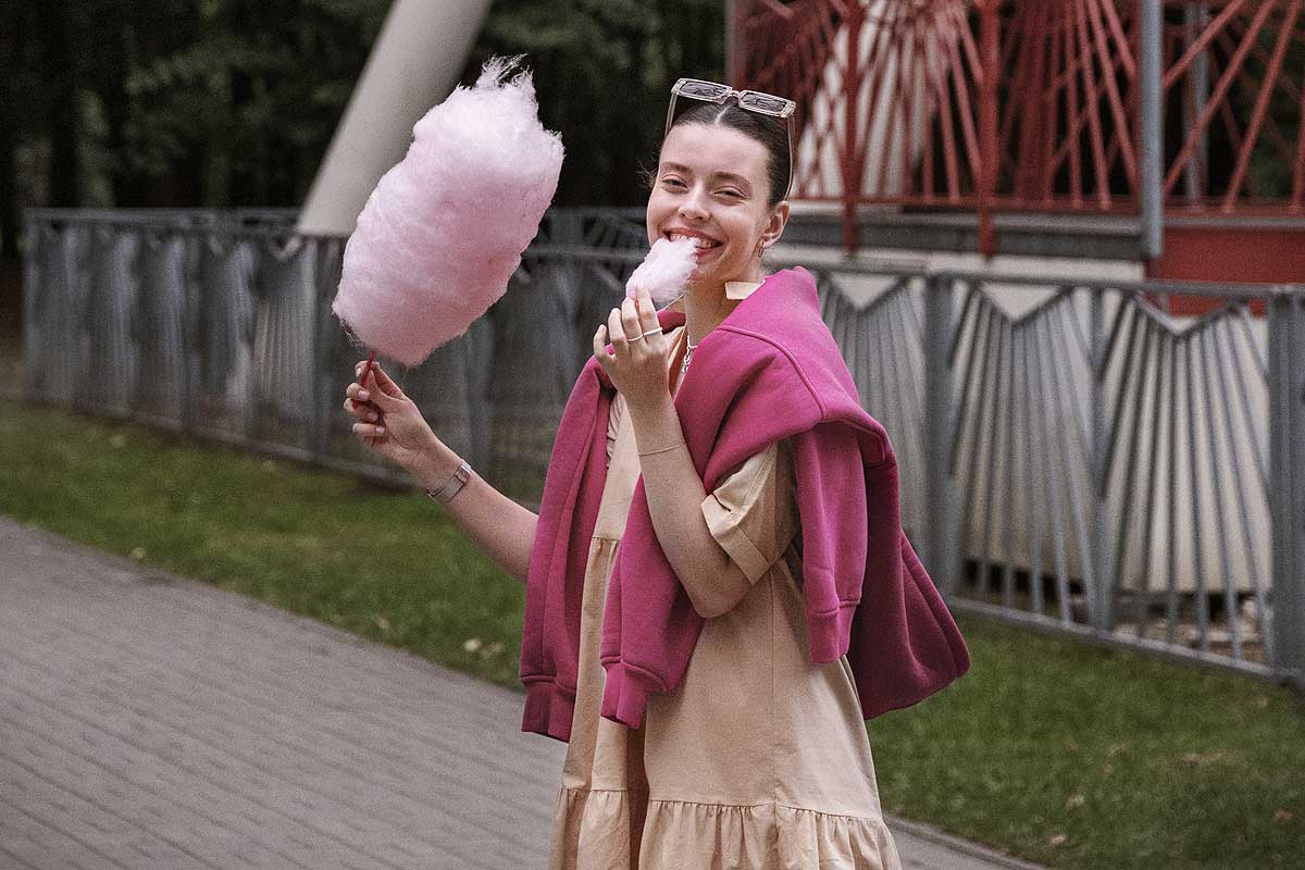 Uma mulher sorridente come algodâo doce na Disney. Créditos da imagem: freepik.com