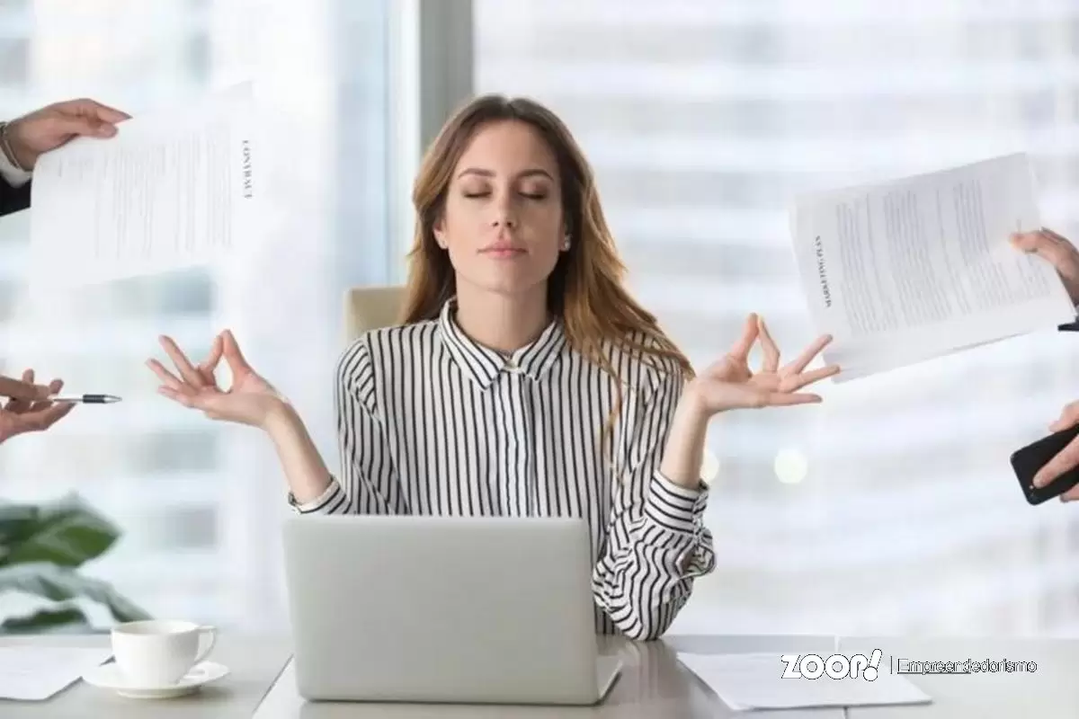 Uma mulher em estado zen no ambiente de trabalho ilustra nosso artigo sobre: Como criar uma rotina equilibrada com a ajuda da tecnologia. Uma mulher em estado zen no ambiente de trabalho ilustra nosso artigo sobre: Como criar uma rotina equilibrada com a ajuda da tecnologia.